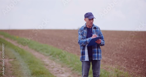 Rural worker checking notes in a cultivated field