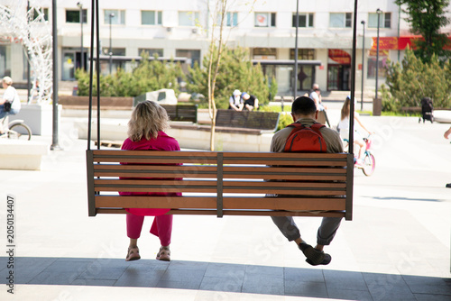 Distance between a woman and a man. A man and a woman sitting on a swing.