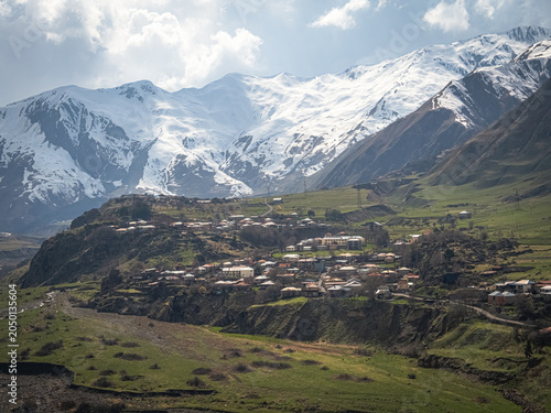 Snow-capped peaks tower above a quiet village. Georgia.