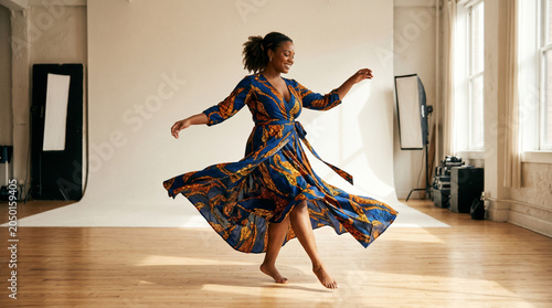 Confident African American Woman Dancing in Flowing Blue Dress inside Bright Photo Studio