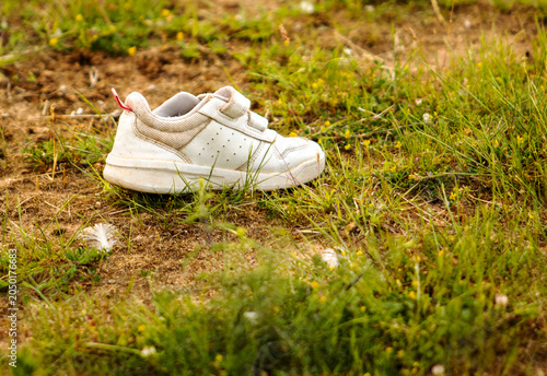 An abandoned white child's shoe on the grass