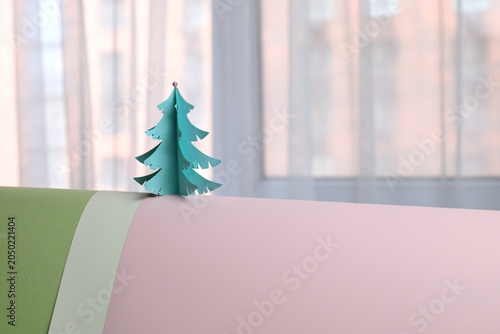 A paper Christmas tree against the window. Pastel colors. Waiting for the holiday.