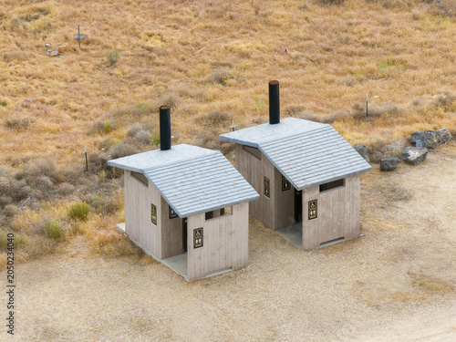 Drone shot reveals two rustic wooden restrooms with gray roofs