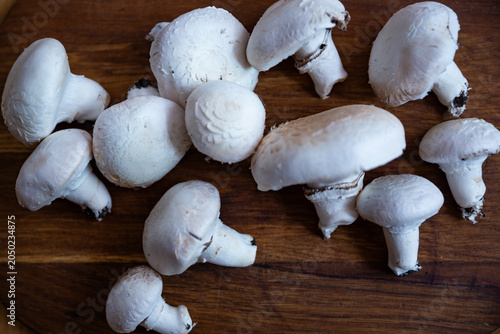 Fresh white Agaricus mushrooms on a wooden cutting board