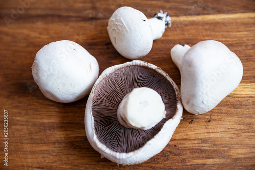 Fresh white Agaricus mushrooms on a wooden cutting board
