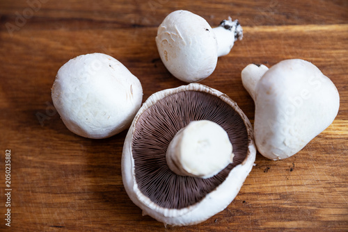 Fresh white Agaricus mushrooms on a wooden cutting board