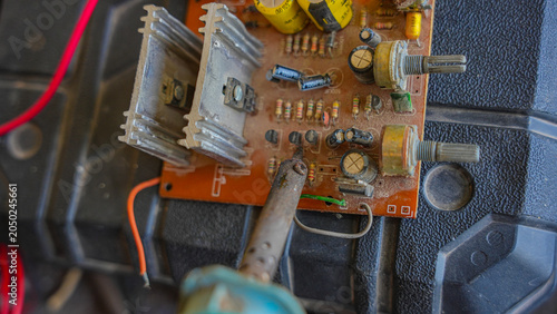 Bild auf Leinwand A soldering iron tip is precisely placed on a component on a dusty electronic circuit board, with wires connected