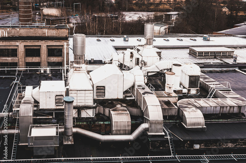 Roof view of old industrial building in Molndal Sweden showing fans and ventilation systems near city structures