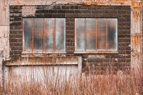 Abandoned factory in Sweden shows broken windows and overgrown grass with signs of age and neglect over time