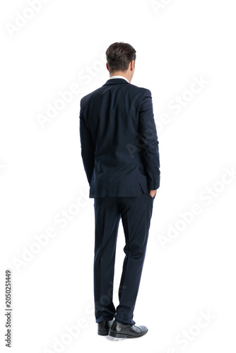 Back view of elegant man standing with hands in pockets