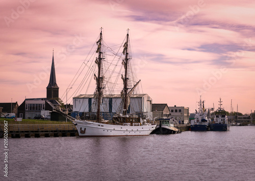 Traditional sailing boats moored in the harbor of Lemmer, Netherlands, with part of the historic town visible in the background. A peaceful maritime scene capturing Dutch coastal heritage.
