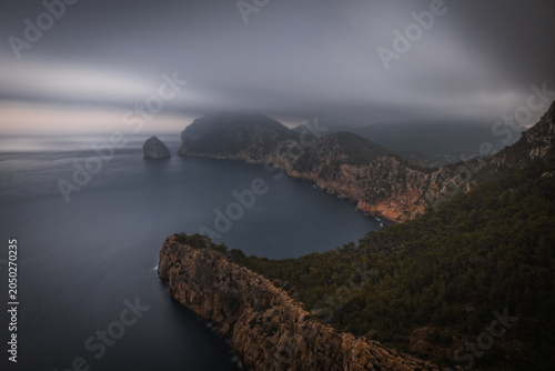 View from the Mirador Es Colomer towards the island Colomer and the mountain range on Formentor peninsula, cloudy sunrise. Mallorca, Spain, October 2024. Long exposure picture