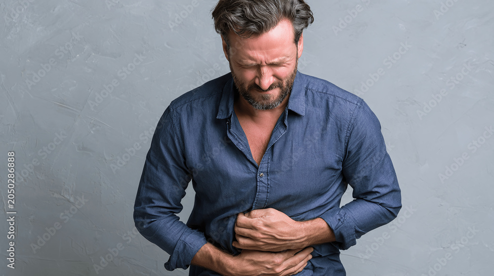 Fototapeta premium A man experiencing stomach pain, clutching his abdomen in distress