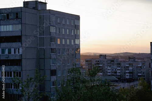 Soviet-era apartment blocks at dusk with distant hills