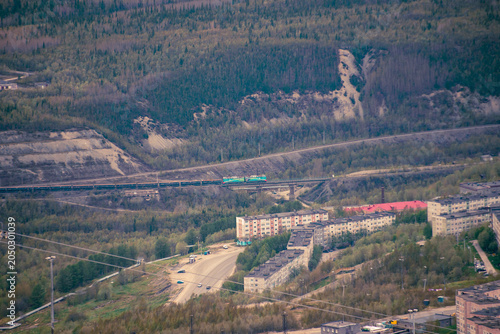 Suburban apartment blocks and freight train passing through forested valley