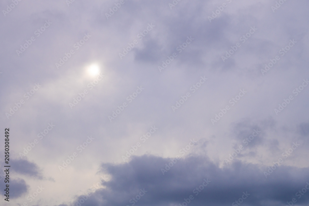 Fototapeta premium Moody overcast sky background with sun breaking through grey clouds