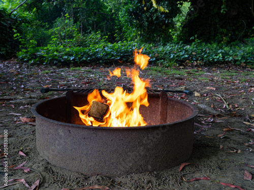Bright orange flames burning firewood inside a metal ring at a campsite