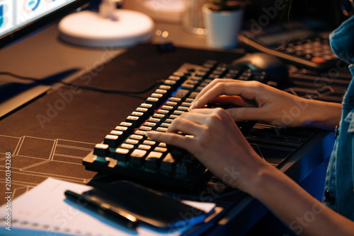Schilderij op canvas Cropped image in young beautiful Asian creative woman typing on keyboard to search new project creator social media online on pc to make strategy market at neon modern office at night
