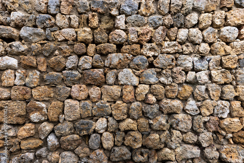 Ancient stone wall. Architectural pattern of a historic building's wall made with roughly shaped stones.