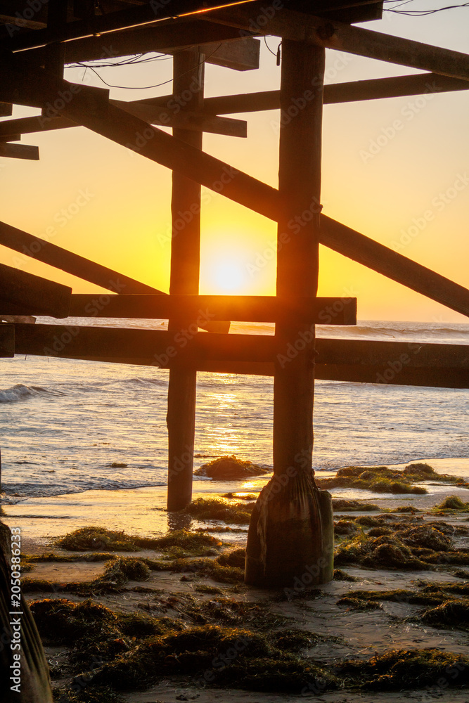 Obraz premium Golden sunset shining through wooden support beams beneath Crystal pier at Pacific Beach, San Diego, California