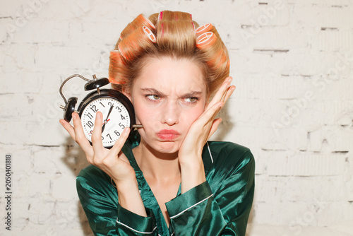 Funny portrait of young woman holding alarm clock. Time management and morning routine concept.