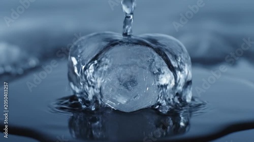 Heart shaped ice melts slowly in water with ripples.