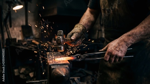 Blacksmith hammering glowing red hot iron on anvil, creating bright sparks in a dark forge workshop