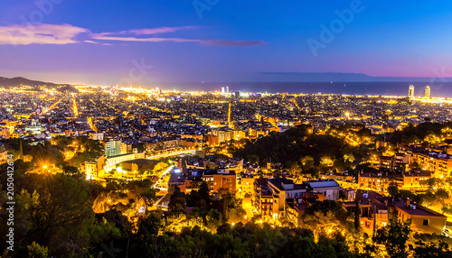 Panoramic twilight view of a sprawling coastal city illuminated by glowing lights, urban landscape, skyline, sea horizon