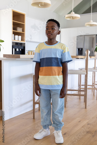 Foto African American boy age nine standing in kitchen by island under pendant lights