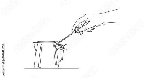 Fotografie Hand stirring liquid in metal pitcher using long whisk.