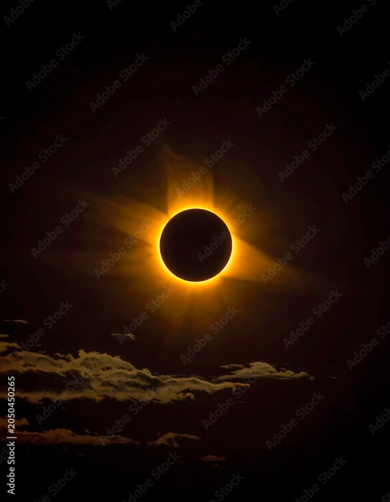 Obraz premium A dark disk centered in a glowing yellow ring, surrounded by rays