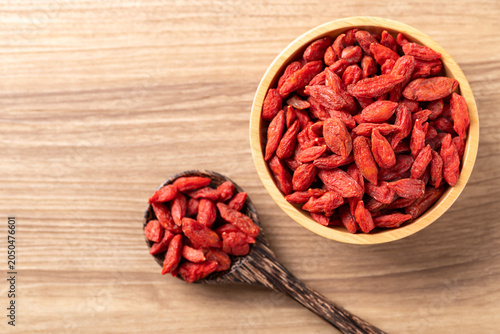 Fotografía Organic dried goji berries in a bowl and spoon on wooden background
