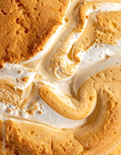 A close-up of a dessert with a yellow crust and white creamy swirls