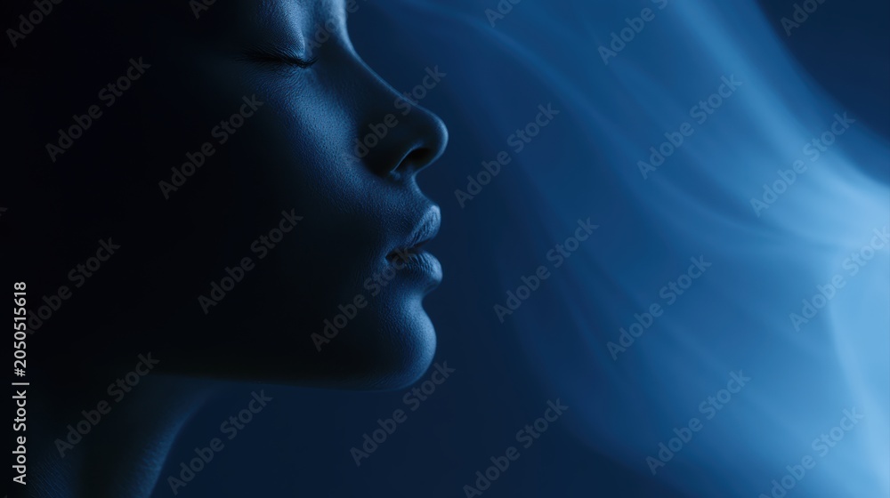 Obraz premium Calm face illuminated by subtle blue ambient glow with flowing holographic smoke on dark background, elegant minimal composition