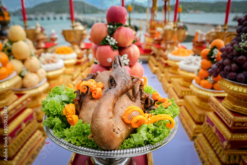Ceremony offering roast duck fruit altar candle incense bouquet, traditional waterfront shrine table with golden tray, colorful harvest display, festive devotion