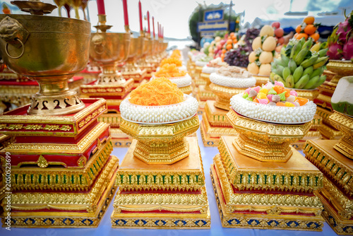 Religion offering altar gold tray fruit candle incense, ornate pedestal set for Buddhist ceremony near temple, vibrant color and festive devotion, soft focus background