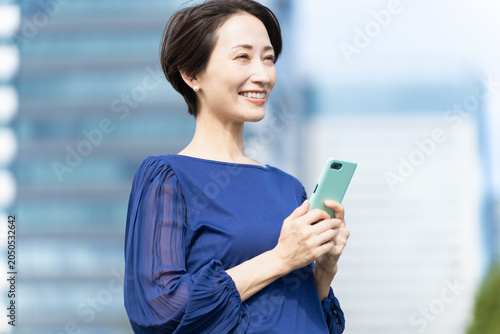 Quadro su tela ビル街でスマートフォンを操作している女性