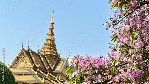 Bild auf Leinwand Vibrant purple flowers bloom before the golden architecture of the Royal Palace in Phnom Penh