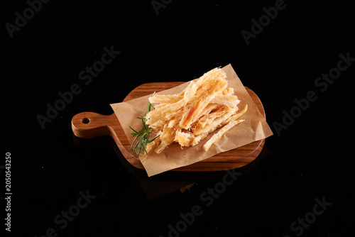 Canvastavla Dried Shredded Squid Strips and Chewy Jerky Snack on Wooden Platter over Black B