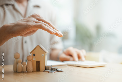 Foto Family protection and life insurance concept with miniature house, family figures, and savings coins under a protective hand