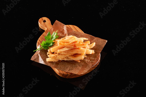 Roasted Shredded Squid Snack with Parsley on Wooden Board over Black Reflective Background