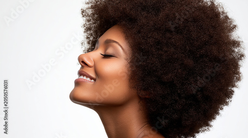 Woman with afro hairstyle smiling with eyes closed in profile portrait wellness