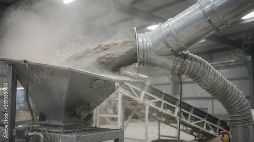 Closeup medium shot capturing a dust collector unit connected to a metal chute demonstrating effective fugitive dust extraction during material transfer.