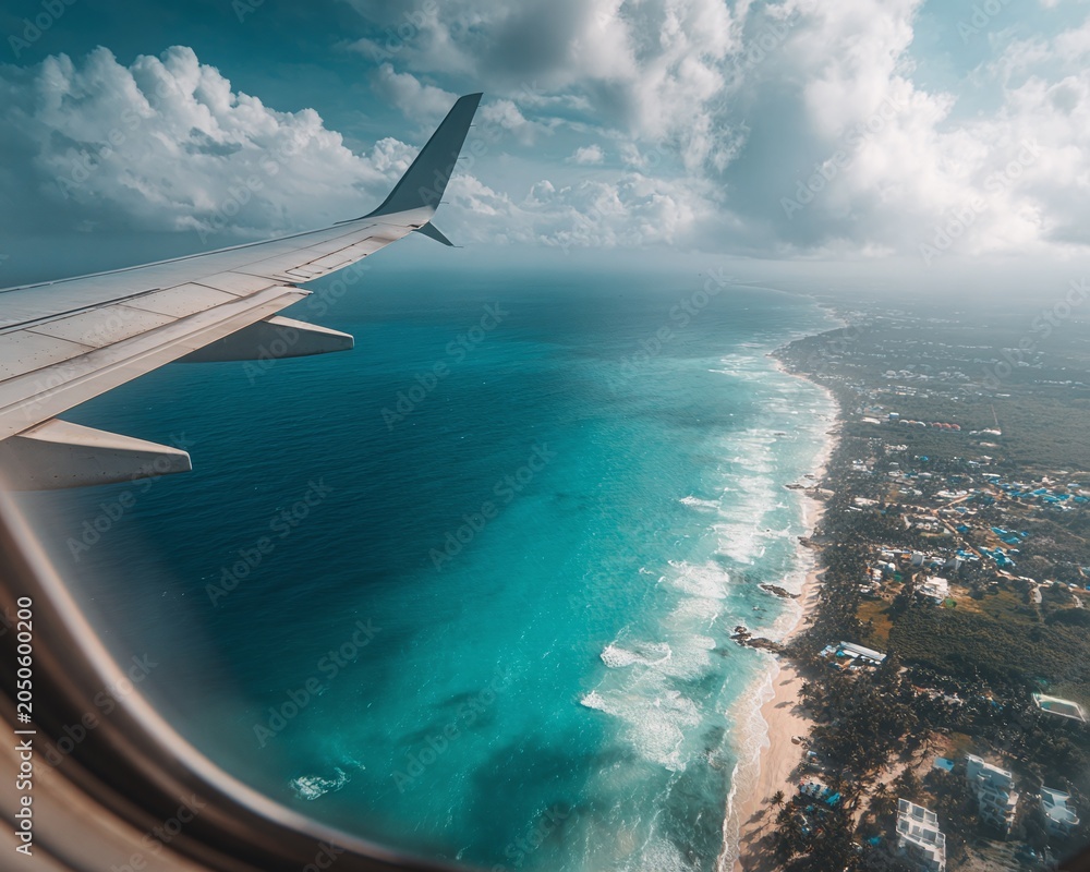 Obraz premium Airplane wing over ocean and coastline.
