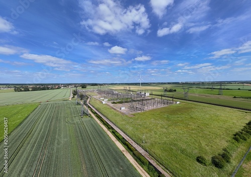 Petite centrale électrique rurale en Meurthe-et-Moselle. Vue aérienne panoramique des installations électriques, transformateurs, pylônes, câbles, répartiteurs. Au milieu des champs et des cultures.