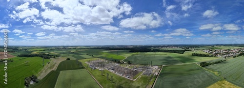 Petite centrale électrique rurale en Meurthe-et-Moselle. Vue aérienne panoramique des installations électriques, transformateurs, pylônes, câbles, répartiteurs. Au milieu des champs et des cultures.
