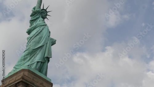 Statue of Liberty on Liberty Island, New York, United States. Blue cooper monument, symbol of democracy and patriotism near Manhattan, NYC USA. Clouds on sky. American independence. Torch and crown.