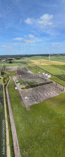 Petite centrale électrique rurale en Meurthe-et-Moselle. Vue aérienne panoramique des installations électriques, transformateurs, pylônes, câbles, répartiteurs. Au milieu des champs et des cultures.