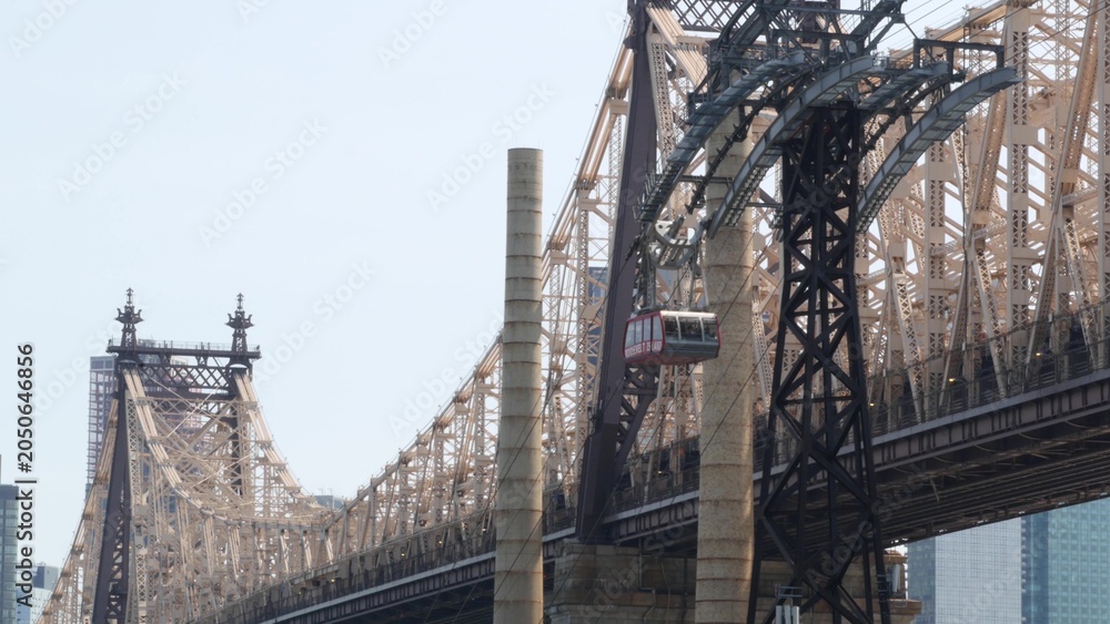 Fototapeta premium New York City Manhattan Midtown, Queensboro bridge architecture in United States. Urban public transport, tramway to Roosevelt island over East River. Red tram cabin car. Metallic bridge in East Side.