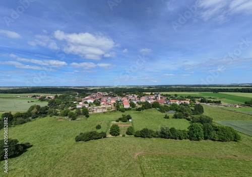Vue aérienne panoramique du village de Laix, en Meurthe-et-Moselle, Lorraine. La commune rurale avec ses habitations et ses bâtiments entourée de champs et de cultures. Ciel bleu et nuages